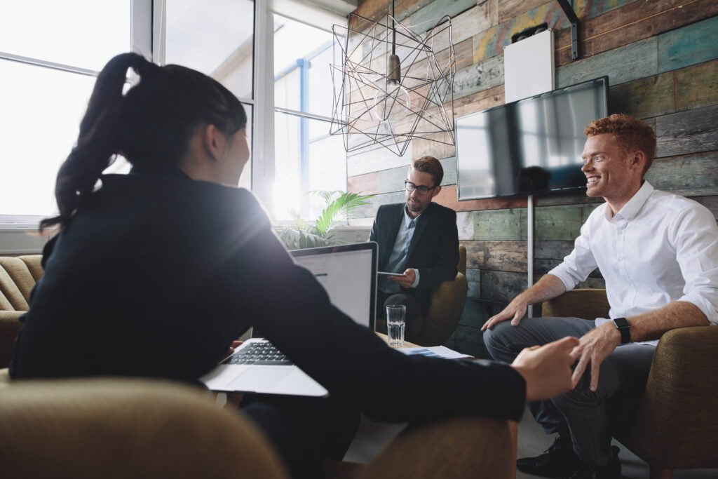 Young man sitting in discussing business with colleagues. Business professionals in meeting room.