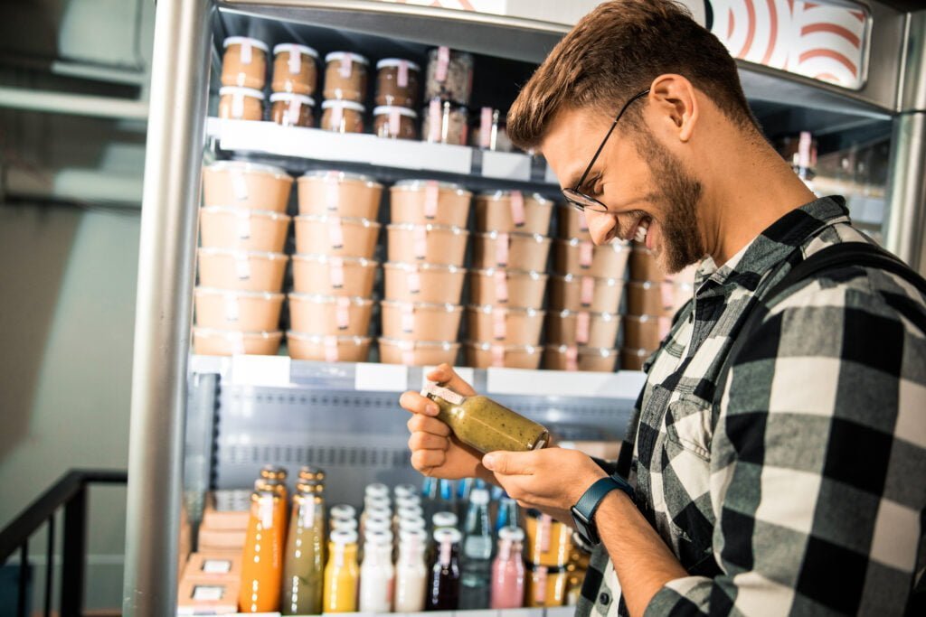 Side view of happy man holding bottle with sauce in supermarket stock photo